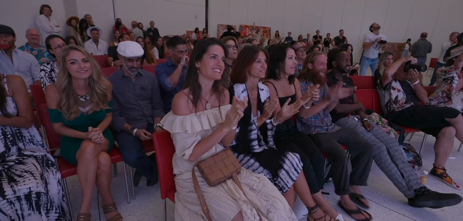 A packed room laughing and leaning in